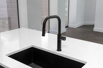 A kitchen sink with a black faucet in a new home